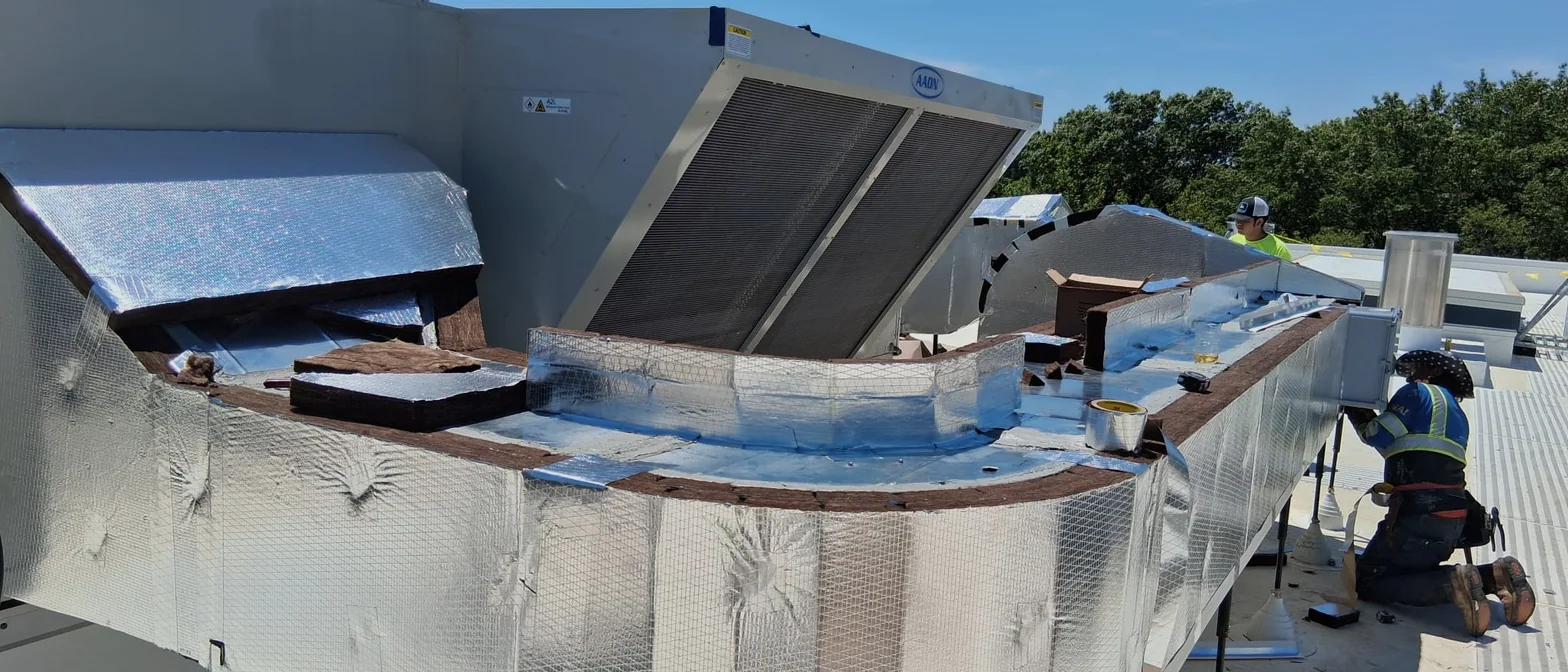 Insulator fitting reflective foil jacketing around a curved rooftop plenum