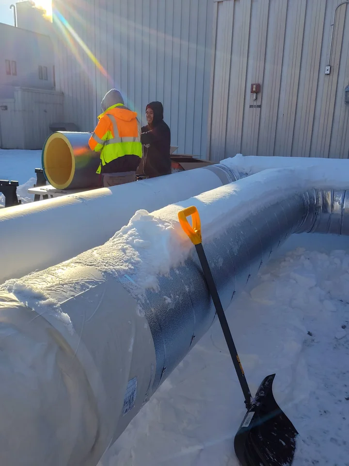 Sabaoth FQ crew insulating jacketed ductwork in the snow, winter jobsite