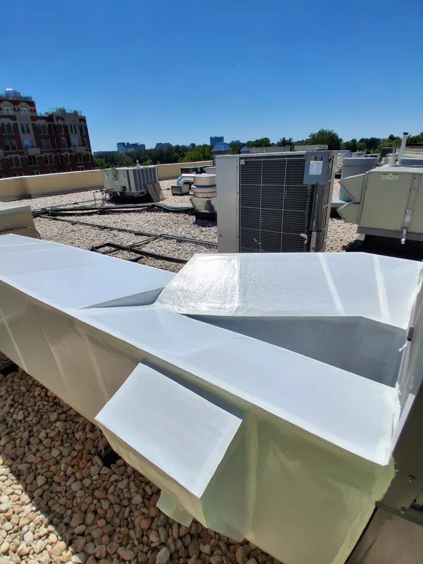 Wrapped rooftop ductwork over a gravel ballast roof