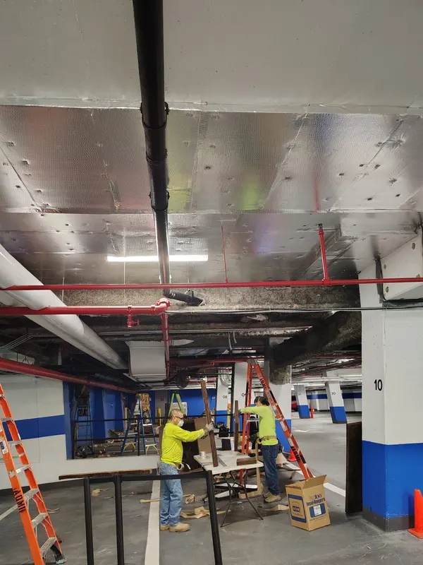 Sabaoth FQ crew staging material under a parking garage ceiling mid insulation