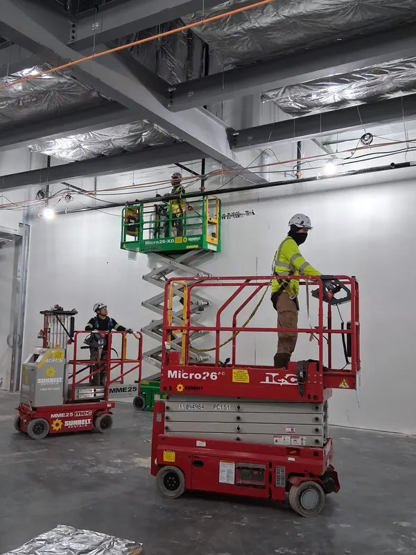Crew lifts staged inside a commercial building during insulation work
