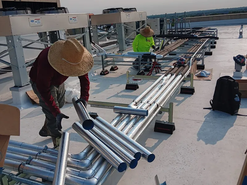 Sabaoth FQ crew staging aluminum pipe jacketing on a commercial rooftop