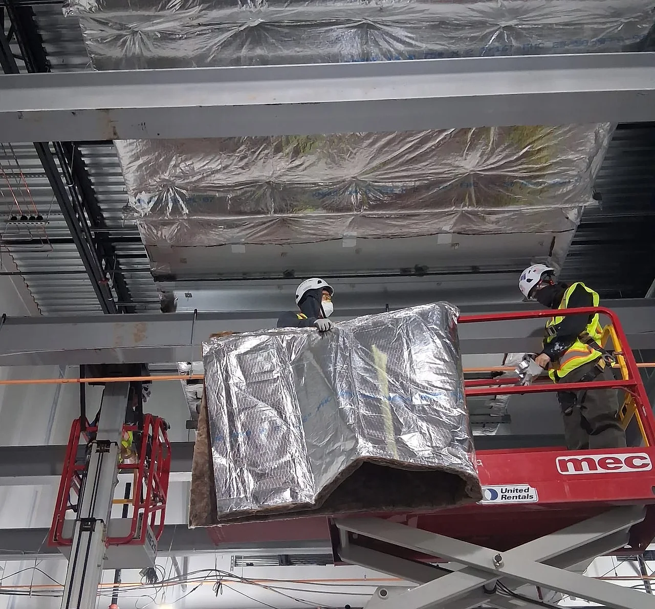 Sabaoth FQ crew hoisting a foil wrapped duct section from a lift inside a commercial building