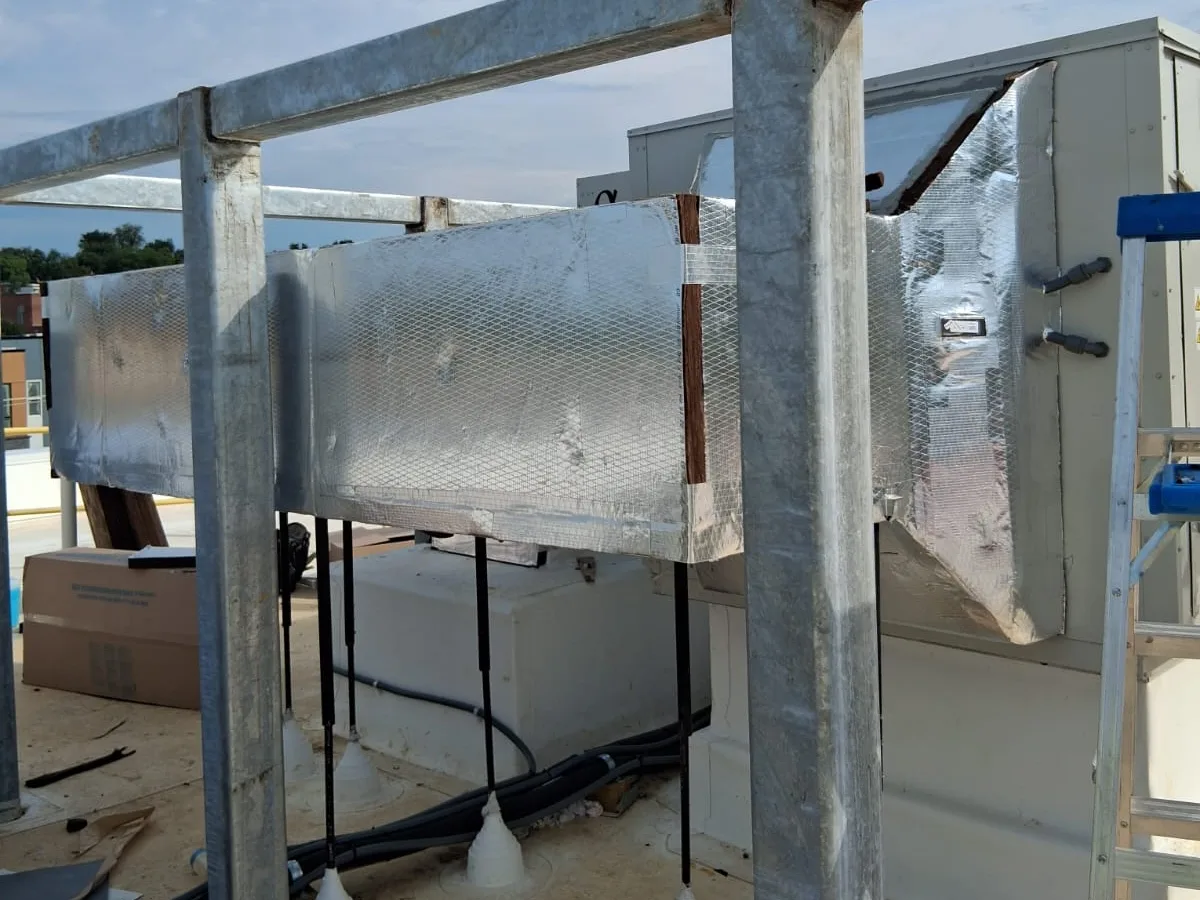 Exhaust duct wrapped in foil faced insulation on a commercial roof