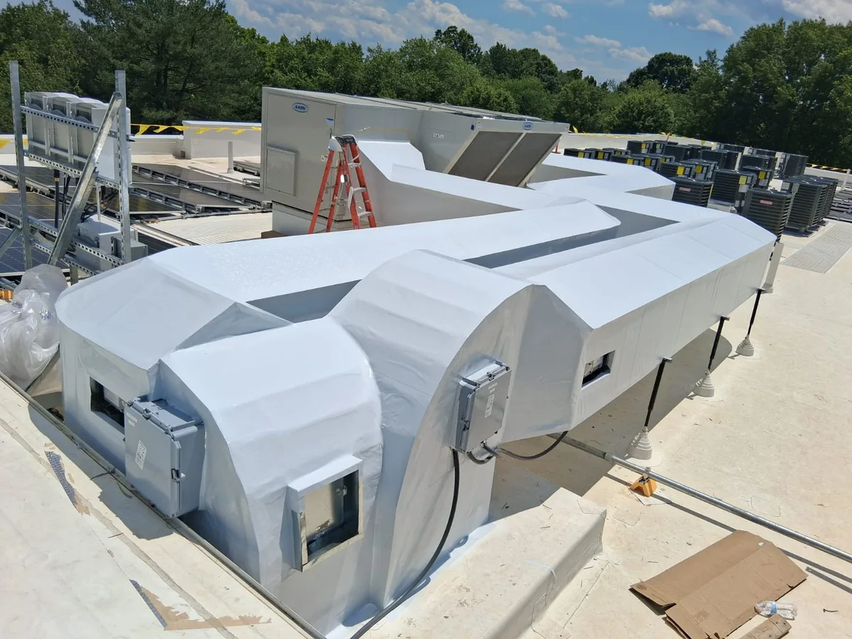 Rooftop HVAC ductwork mid insulation on a commercial building