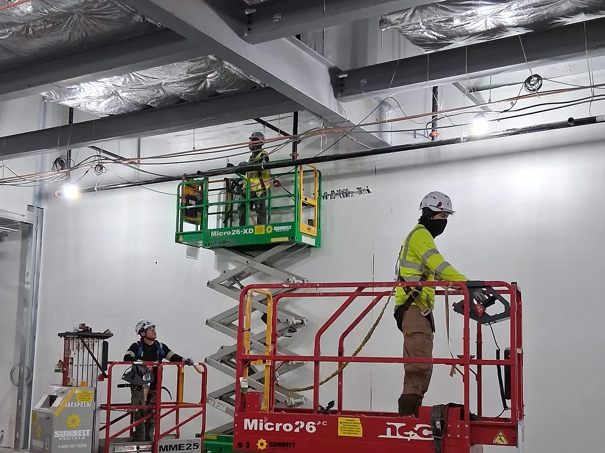 Crew insulating the envelope of a commercial building from scissor lifts